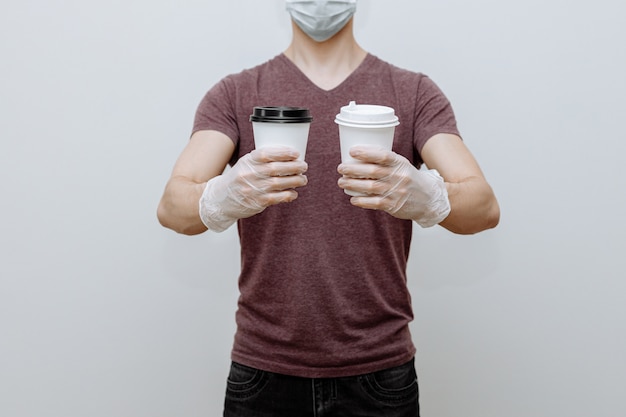 Contactless delivery of coffee by a courier in a mask and gloves from a store or restaurant.