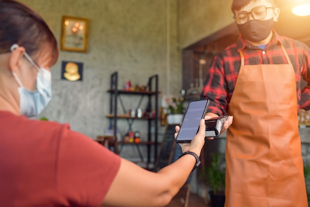 Contactless payment method. Closeup of a customer using her smartphone and nfs technology to payment