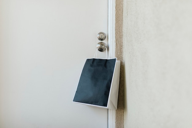 Contactloze levering blauwe papieren zak die aan een deurknop hangt tijdens de coronaviruspandemie