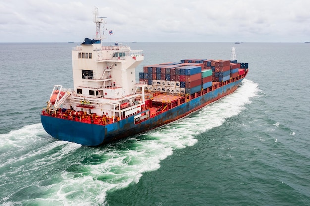 Container cargo ship sailing full speed in green sea to\
transport of goods