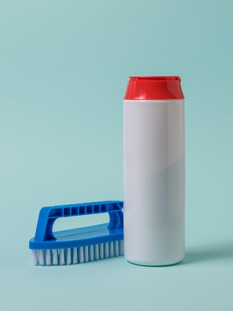 A container of cleaning powder and a blue brush on a blue background