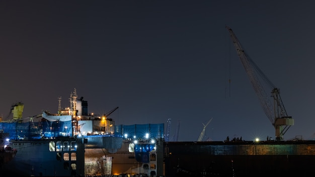 Container oil ship repair in shipyard at night. Can use for shipping or transportation concept.