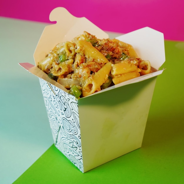 A container of pasta with a green and purple background.