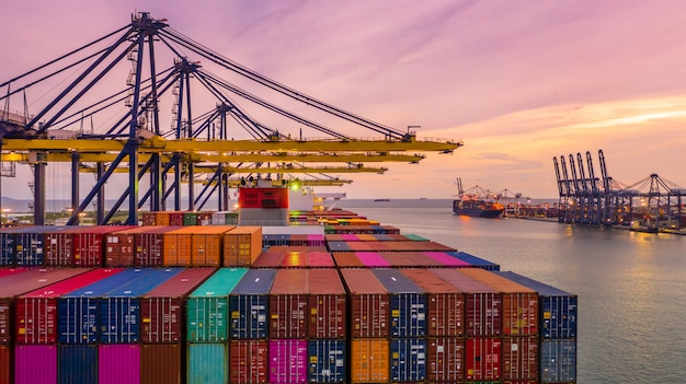 Container ship loading and unloading in deep sea port at sunset, Aerial view of business logistic import and export 