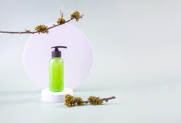 container with cosmetics on a round podium and a tree branch with moss