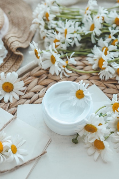 container with cream and chamomiles on wooden background