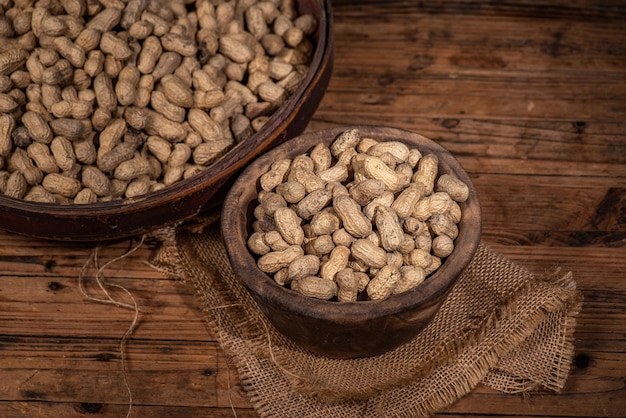 The container on the wood grain table is full of peanuts