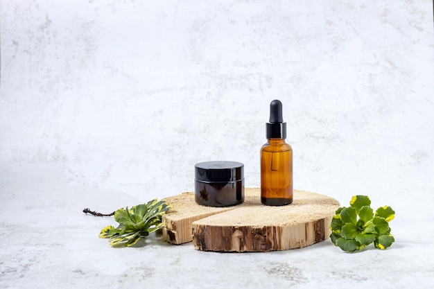 Containers for cosmetics on the podium made of cut wood and green flower leaves