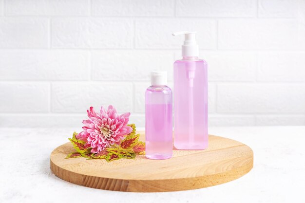 Photo containers for hygiene products on a wooden board and a flower on a gray background