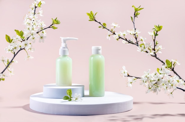 Containers voor cosmetica op een rond wit podium en takken van pruimenbloesems op een beige achtergrond