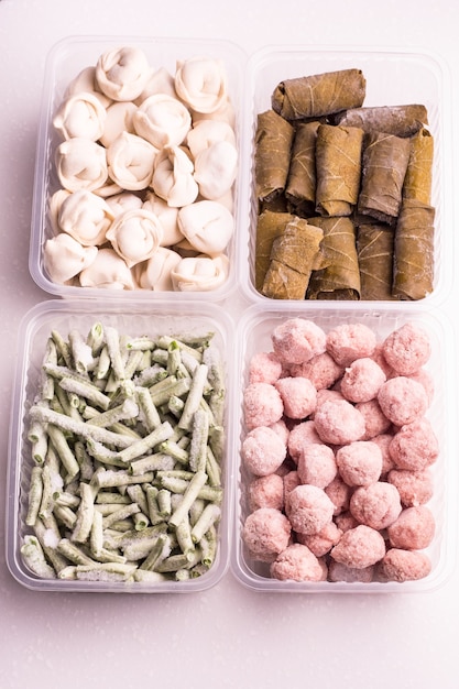 냉장고에서 냉동 야채 및 반제품 육류 제품이 담긴 용기. 미트볼, 만두, 포도잎 돌마, 다진 콩