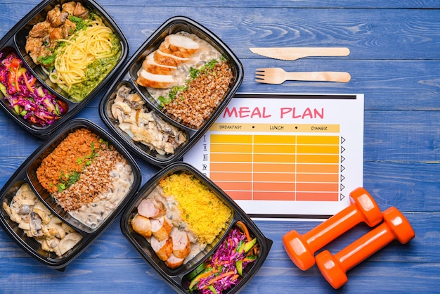 Containers with healthy food, dumbbells and meal plan on color