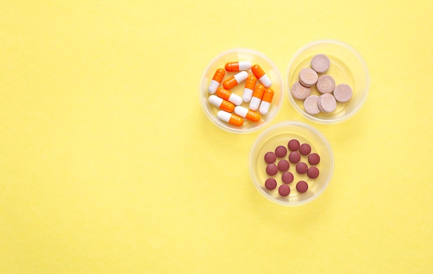 containers with various pills on a yellow background View from above