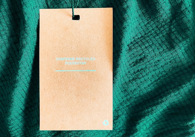 Contains recycled polyester fashion label tag sale price card on luxury emerald green fabric background shopping and retail