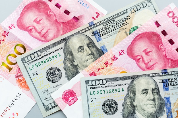 Contant geld: honderd Amerikaanse dollars en honderd Chinese yuan op grijs