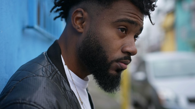 A contemplative black man standing in street