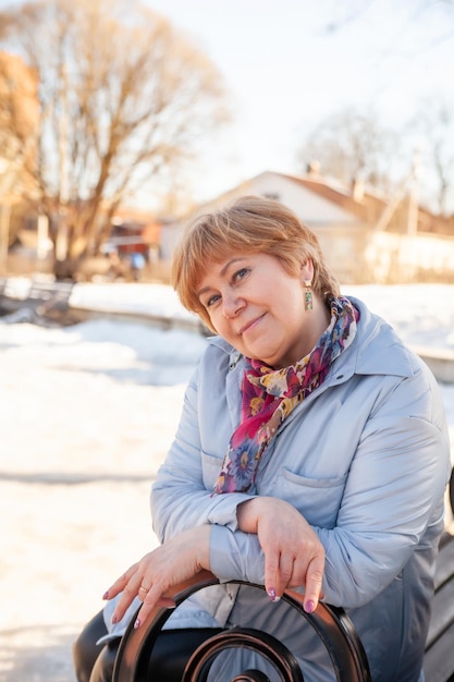 Contemplative casual mature woman sitting on bench in spring park