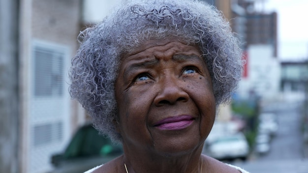 A contemplative senior black woman looking up at sky an african\
person eyes looks up