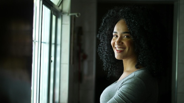 A contemplative young woman standing by window looking outside