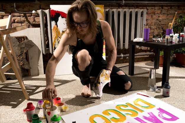 contemporary artist painting on floor in studio