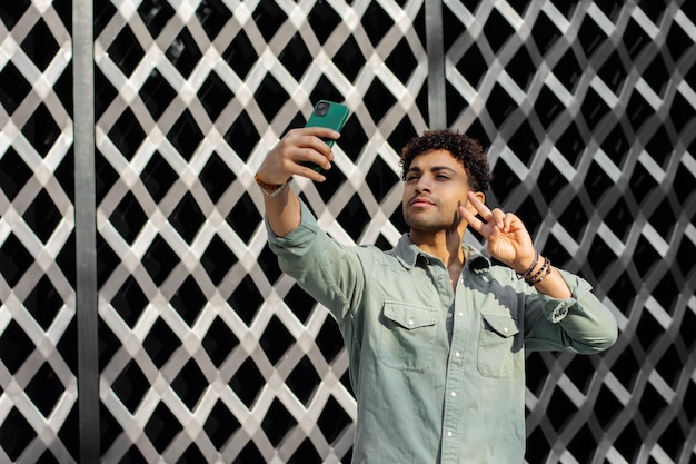 Contemporary brunette man taking a selfie in patterned wall