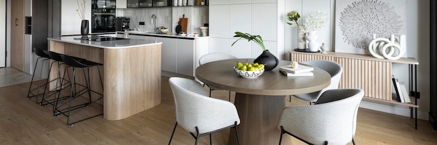 Design contemporaneo dell'interno della sala da pranzo con tavolo rotondo, sedie  grigie, pavimento in legno, decorazioni, fiori in vasi, dipinti ed eleganti  accessori personali. elegante modello di arredamento per la casa