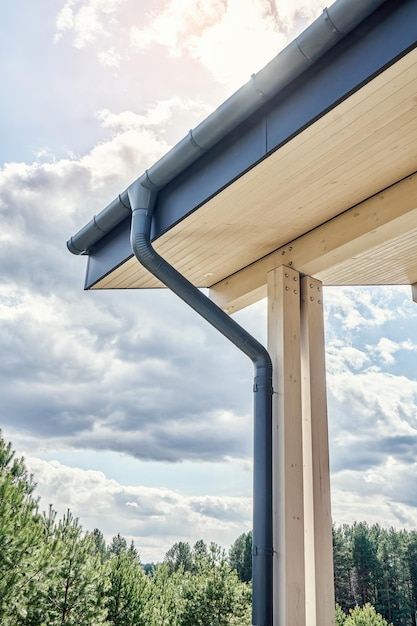 曇りの日のクローズ アップに新しい建物の屋根に設置された現代的な灰色の金属雨水縦樋