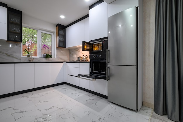 A contemporary kitchen with white cabinets and oven open