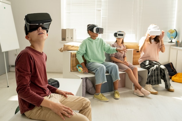 Contemporary schoolboy and his classmates watching video presentation