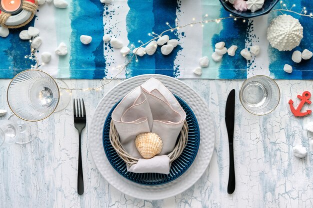 Contemporary summertime table setting with nautical sea decorations on blue and white stripy runner,