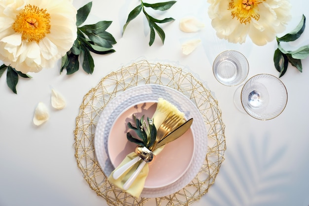 Фото Современная сервировка стола с цветами пиона и золотой посудой на белом столе
