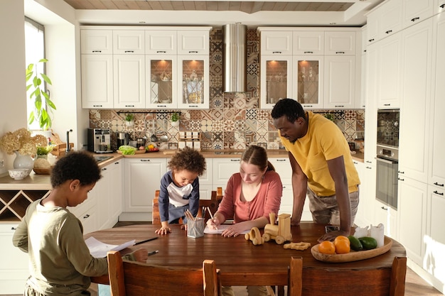 Contemporary young family of parents and two little sons drawing together