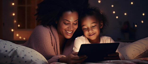 Content black mother and daughter enjoying laptop together in bed open area for text wide view