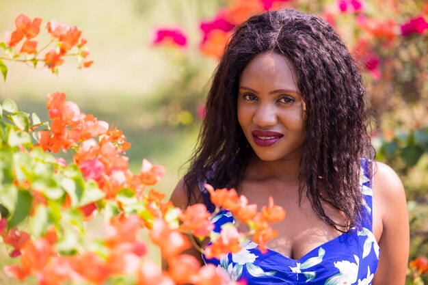 Content Black Woman Smelling Flowers In Park.