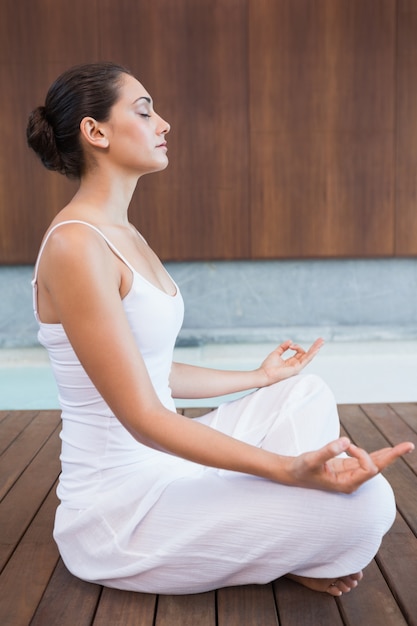 Content brunette in white sitting in lotus pose 