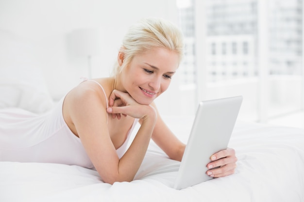 Content casual young blond using tablet PC in bed