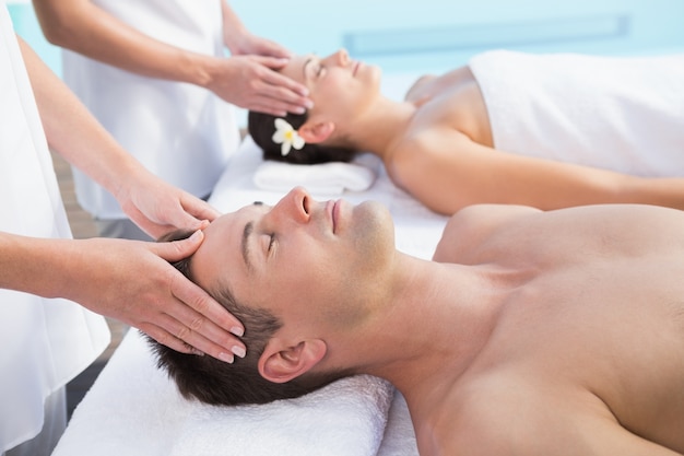 Content couple enjoying head massages poolside