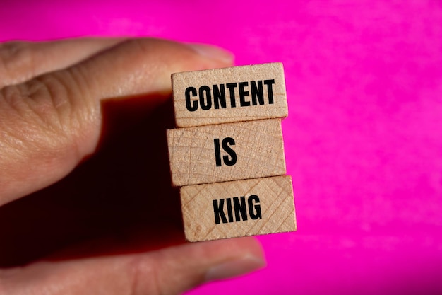 Photo content is king words written on wooden blocks with pink background