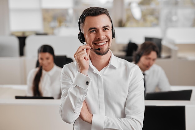 Photo content male employee talking via mic of headset during work in call center