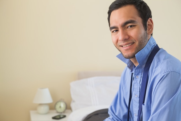 Content man looking at camera and relaxing sitting on his bed