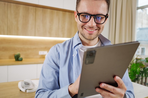 Content professional with glasses using a tablet in a modern welllit office setting exuding