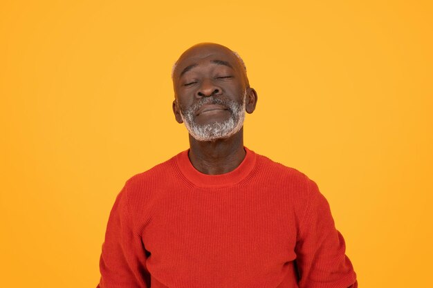 Photo content senior black man with closed eyes and a peaceful smile wearing a red sweater