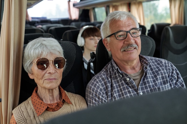 Content senior caucasian couple with gray hair sitting in bus while travelling together