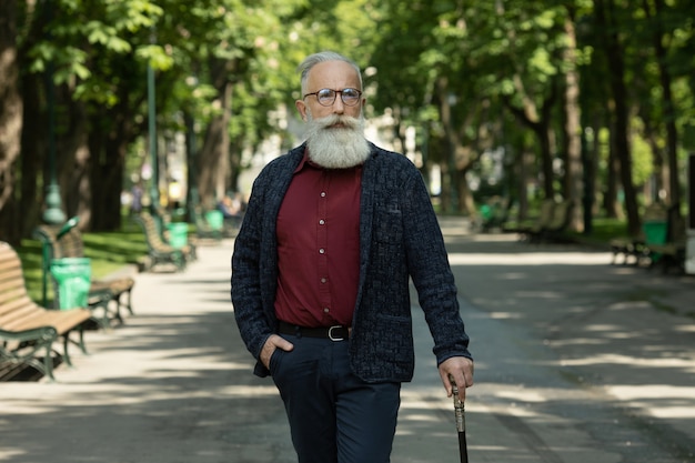 Content senior man with a beard and wearing glasses outdoor.