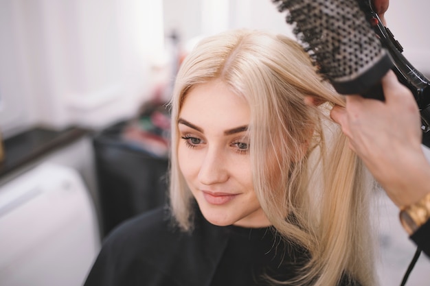 Donna contenta che gode dei capelli che designano nel salone