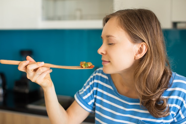 Photo content woman smelling food on wooden paddle