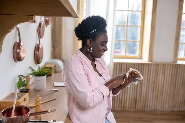 Contented african woman in pink clothes drying hands