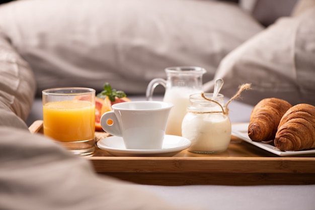 Continentaal ontbijt. Ontbijtdienblad op bed met koffie, jus d'orange en croissant close-up