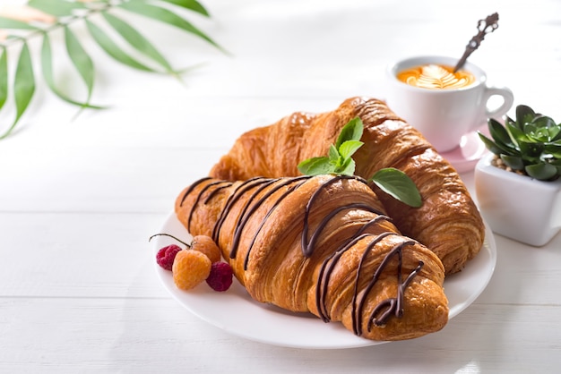 Continentaal ontbijt, versgebakken croissant, versierd met jam en chocolade