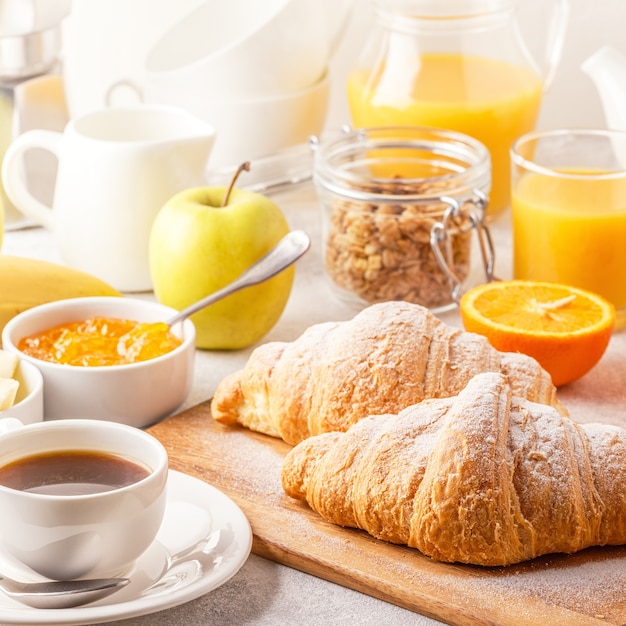 Foto colazione continentale con croissant freschi, succo d'arancia e caffè, focus selettivo.